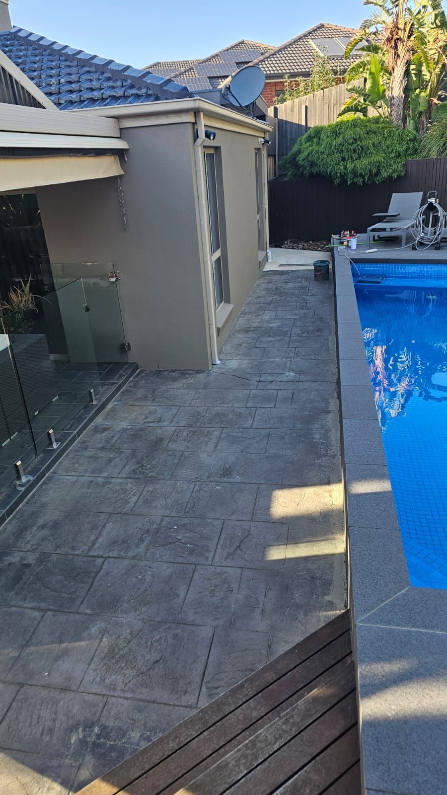 Cracked stamped concrete pool surround before resurfacing