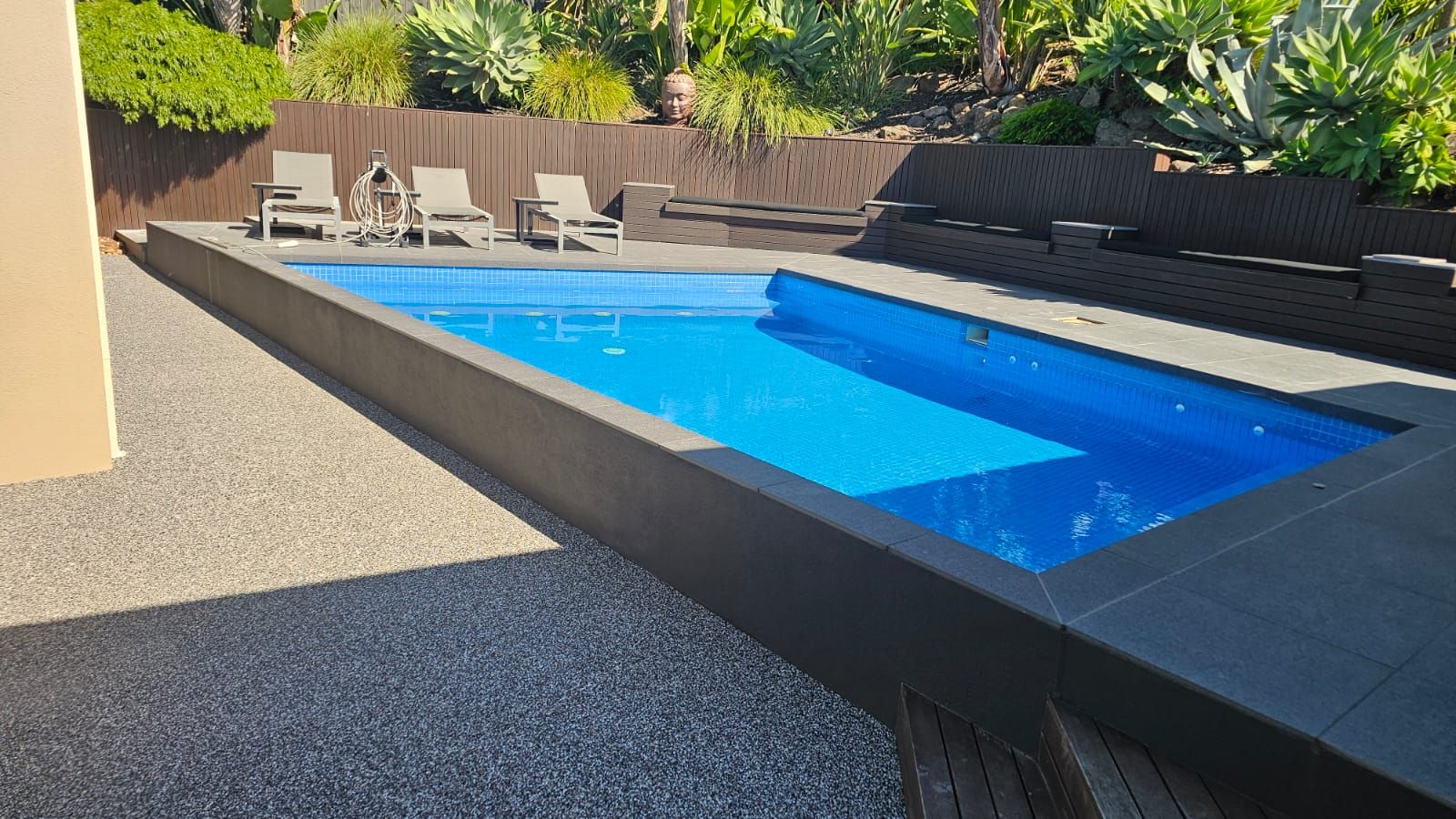 Pool surround finished in Dolomite resin bound stone beside the charcoal coping