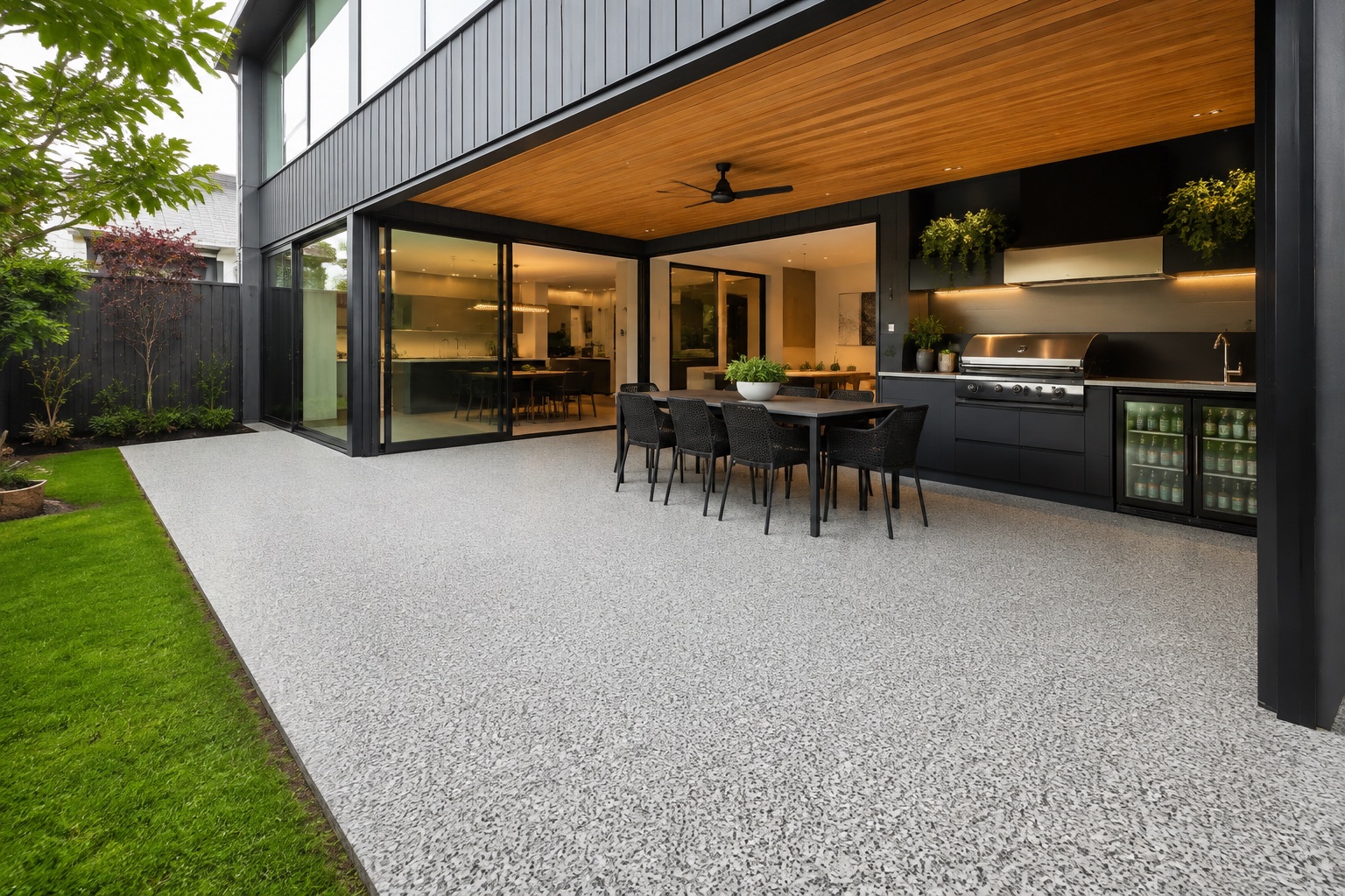 Resin bound alfresco area in light grey aggregate flowing from the outdoor kitchen and dining space to the lawn