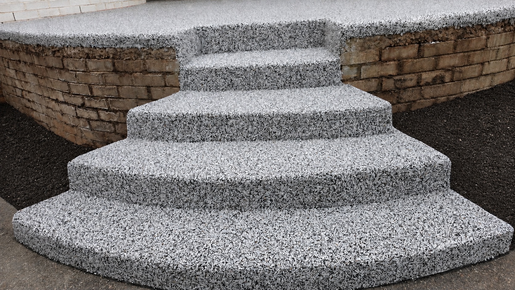 Curved front steps resurfaced in grey resin bound aggregate between brick retaining walls